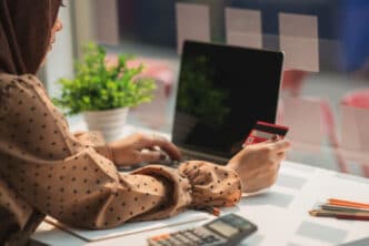 Muslim,Woman,Wearing,Hijab,Using,Laptop,And,Holding,Credit,Card.