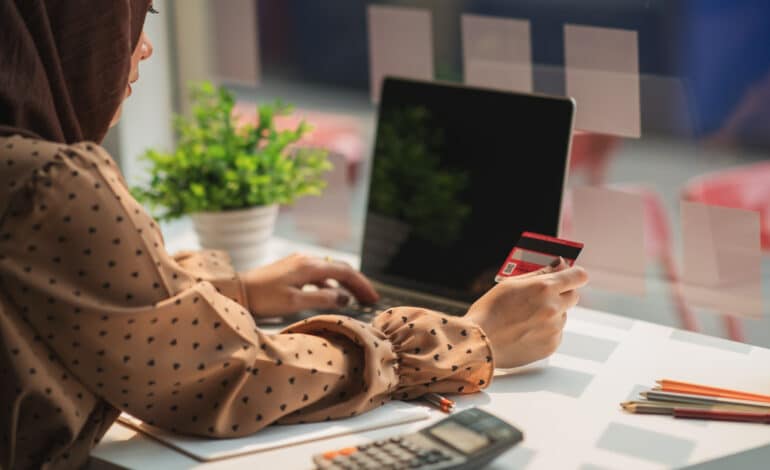 Muslim,Woman,Wearing,Hijab,Using,Laptop,And,Holding,Credit,Card.